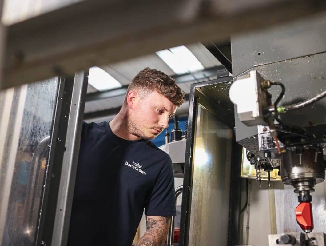 DaceCrown engineer in branded workwear working at a CNC machining centre with the enclosure door open